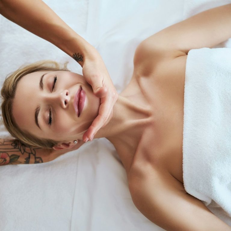 Vrouw ligt in de behandelstoel en geniet van een ontspannende gezichtsmassage bij Just Your Glow in Maastricht